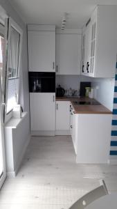 a white kitchen with white cabinets and a window at Apartament Nadmorski LUX1 in Sztutowo