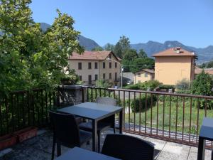 een tafel en stoelen op een balkon met bergen op de achtergrond bij La Tana Rooms in Lenno