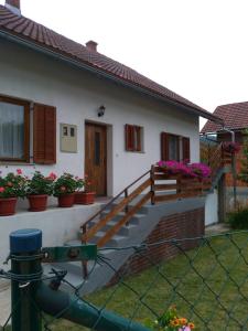 a house with a staircase and flowers in pots at Apartman NINA in Ličko Petrovo Selo