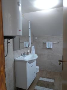 a white bathroom with a sink and a mirror at Apartman NINA in Ličko Petrovo Selo +56 photos