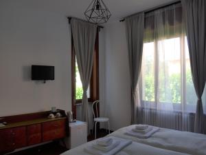 a bedroom with a bed and a window with a television at La Tana Rooms in Lenno
