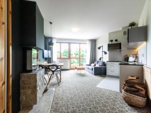 a kitchen and living room with a fireplace and a table at VacationClub – Cristal Resort Apartament 414 in Szklarska Poręba