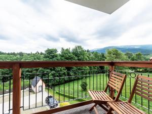 2 sillas en un balcón con vistas a un campo en VacationClub – Cristal Resort Apartament 414, en Szklarska Poręba