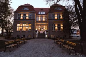 a large house with benches in front of it at Pałac Rajkowo in Szczecin