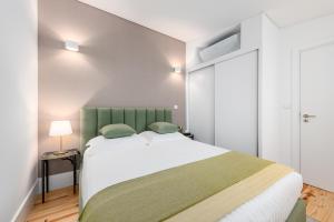 een slaapkamer met een groot bed met een groen hoofdeinde bij Porto Belo Sao Bento Apartment in Porto