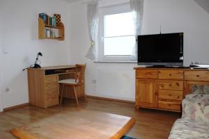 ein Wohnzimmer mit einem Schreibtisch und einem TV auf einer Kommode in der Unterkunft Apartments Anna 58 in Klagenfurt am Wörthersee