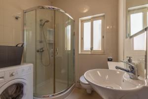 a bathroom with a shower and a sink and a washing machine at Valletta Penthouse in Valletta