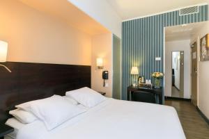 a bedroom with a large white bed and a desk at Hotel Florence Nice in Nice