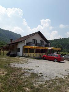 a red car parked in front of a building at Prenoćište Vitas in Miljevina