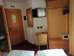 a room with a bed, chair and a television at Garni Baita Cecilia in Livigno