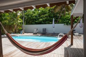 a hammock on a patio next to a swimming pool at Villa Cosy - Grande capacité avec piscine in Le Gosier