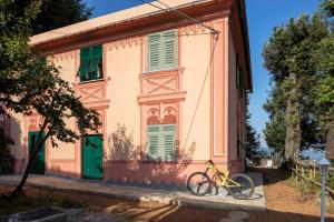 a yellow bike parked in front of a pink house at La BRIGNA B&B Il bosco sul mare in Genoa
