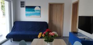 un soggiorno con divano blu e tavolo con fiori di MiLa Home Zamardi - Keszeg a Zamárdi