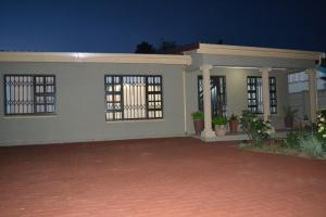 ein kleines weißes Haus mit einer steinernen Einfahrt in der Unterkunft Leago Guesthouse in Bloemfontein