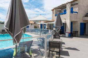 a patio with chairs and umbrellas next to a pool at Hotel Le Bleu Marine in Saintes-Maries-de-la-Mer