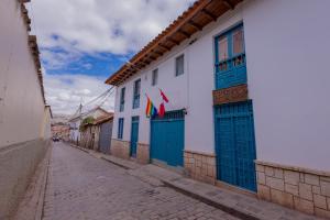 a street in a town with blue doors and flags at Hawka Inka Hostal - Cusco in Cusco