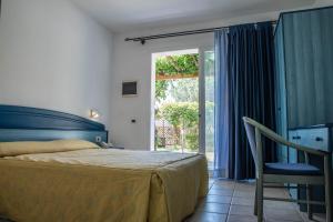 une chambre avec un lit, une chaise et une fenêtre dans l'établissement Nicotera Beach Village, à Nicotera Marina