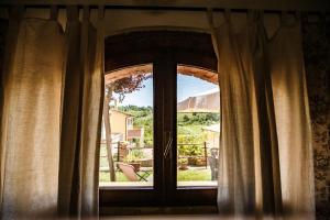 a window with curtains and a view of a yard at Casetta Luna e Sole in Montescudaio
