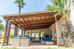 une terrasse avec des chaises bleues et une pergola en bois. dans l'établissement Nicotera Beach Village, à Nicotera Marina