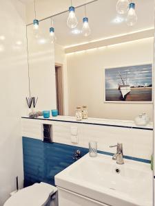 ein Badezimmer mit einem Waschbecken, einem WC und einem Spiegel in der Unterkunft Marine Apartament in Danzig