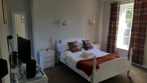 a bedroom with a white bed and a television at Central Bar Guesthouse in Cushendall