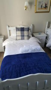 a large white bed with a blue blanket on it at Central Bar Guesthouse in Cushendall