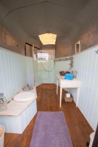 y baño con lavabo, aseo y mesa. en Quex Livery Glamping en Birchington