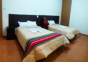 two beds in a hotel room with towels on them at Kantu Progreso Inn in Cusco