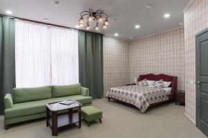 ein Schlafzimmer mit einem grünen Sofa und einem Bett in der Unterkunft Welcome House Boutique Hotel in Rostow am Don