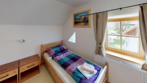een kleine slaapkamer met een bed in een kamer met een raam bij Apartmaji pri Marodnu in Bohinj