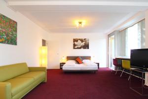 a hotel room with a bed and a couch and a tv at College Garden Hotel in Bad Vöslau