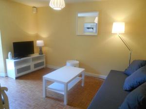 a living room with a couch and a table and a tv at Appartement Vallée de Luchon in Salles-et-Pratviel