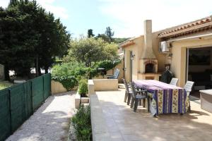 eine Terrasse mit einem Tisch, Stühlen und einem Kamin in der Unterkunft La Garonnette - 150m de la plage in Sainte-Maxime