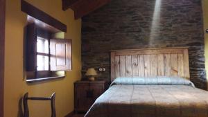 um quarto com uma cama e uma parede de pedra em Casa rural Albina em Susañe del Sil