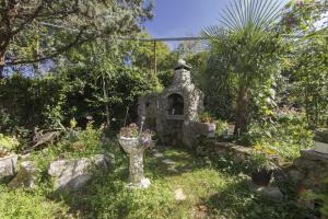 a garden with a stone vase with flowers in it at Rasopasno 2 in Malinska