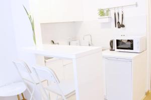 cocina blanca con sillas blancas y microondas en NEW Central Light Apartment with Private Parking, en Novi Sad
