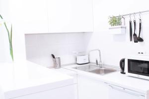 a white kitchen with a sink and a microwave at NEW Central Light Apartment with Private Parking in Novi Sad