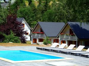 a swimming pool with lounge chairs and a house at Górskie Domki - Szklarska Poręba in Szklarska Poręba