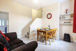 - un salon avec une table, des chaises et une horloge dans l'établissement Cloud View Cottage, à Congleton
