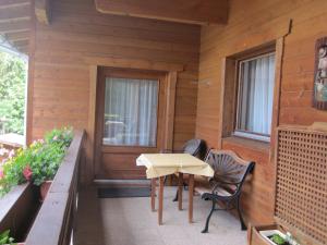 eine Veranda eines Holzhauses mit einem Tisch und Stühlen in der Unterkunft Apartmenthaus Rupitsch in Leutasch
