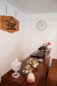 a desk with a laptop and a clock on a wall at Picos House in Machu Picchu