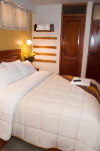 a bedroom with a large white bed and a door at Picos House in Machu Picchu