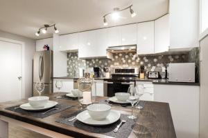 a kitchen with a table with plates and wine glasses at Modern Executive Suite I Complimentary Netflix & Parking! in Edmonton