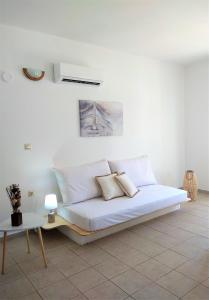 a white bed with two pillows on it in a room at Gompos Apartment - Cozy Apartment next to the sea - Amazing Sea View in Symi