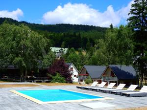 a swimming pool with lounge chairs and a house at Guesthouse BORSZÓWKA by the creek exclusive, with access to a pool, sauna, and hot tub in Szklarska Poręba