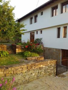 a house with a stone wall in front of a building at Fenix Rooms in Arbanasi