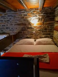 uma cama num quarto com uma parede de pedra em Giataki em Caristo