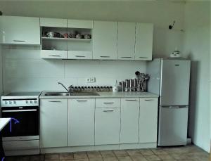 uma cozinha com armários brancos e um frigorífico em Gästehaus Sonnenhöhe - Ihre Erlebnis-Programm-Schmiede em Beuren