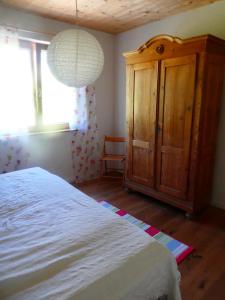a bedroom with a white bed and a wooden cabinet at Ferienwohnung Bodensee Bullerbü in Eigeltingen +1 photo
