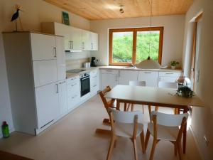 uma cozinha com armários brancos e uma mesa e cadeiras em Ferienwohnung Bodensee Bullerbü em Eigeltingen